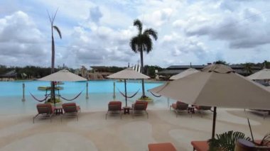 Havuzun yanındaki dinlenme alanında şemsiyeler ve güneşlikler var. Slaytlı ve derin havuzlu su parkı