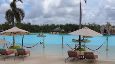 Havuzun yanındaki dinlenme alanında şemsiyeler ve güneşlikler var. Slaytlı ve derin havuzlu su parkı