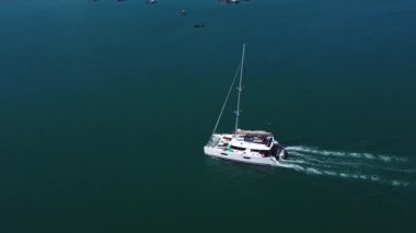 Denizde yüzen bir yatın yüksekliğinden bir manzara, hareket eden bir katamaranın insansız hava aracı görüntüsü.
