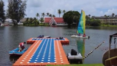 Çocuklar, Phuket 'te pahalı bir otelin özel gölünde küçük bir eğitim botunda yelken açmayı öğrenirler.