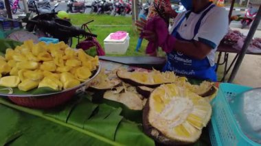 Yapışkan meyve kabuklarını soyan kadın, Tayland pazarında meyveleri soyan kadın.
