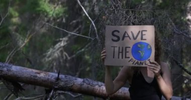 Elinde karton bir afiş tutan güzel bir genç kadın. Ormandaki şapkalı güzel kız. Çevre kirliliği. Gezegeni kurtar. Ekoloji. Yüksek kalite fotoğraf