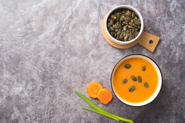 Vejetaryen balkabağı kremalı çorba, gri beton arka planda aperatif, üst manzara.