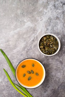 Vejetaryen balkabağı kremalı çorba, gri beton arka planda aperatif, üst manzara.