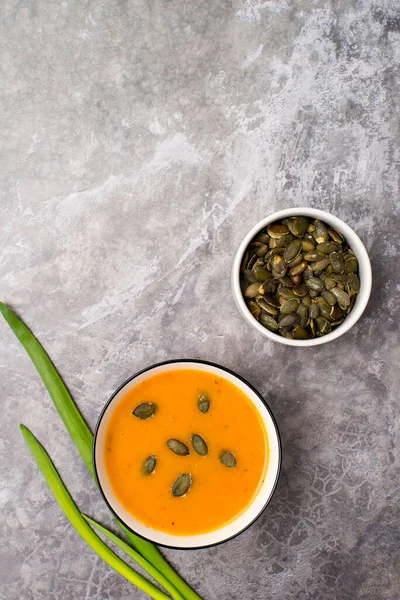 Vejetaryen balkabağı kremalı çorba, gri beton arka planda aperatif, üst manzara.