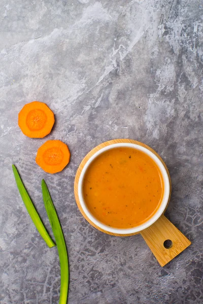 Vejetaryen havuç çorbası, gri beton arka plan, üst manzara.