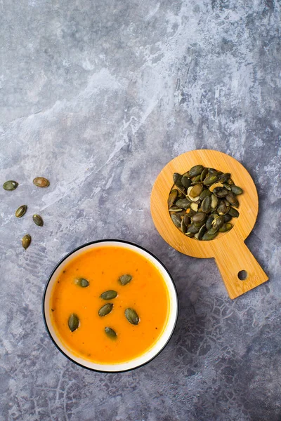 Vejetaryen balkabağı kremalı çorba, gri beton arka planda aperatif, üst manzara.
