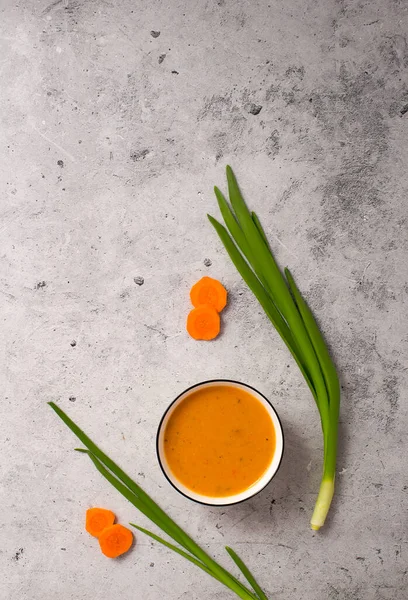 Vejetaryen havuç çorbası, gri beton arka plan, üst manzara.