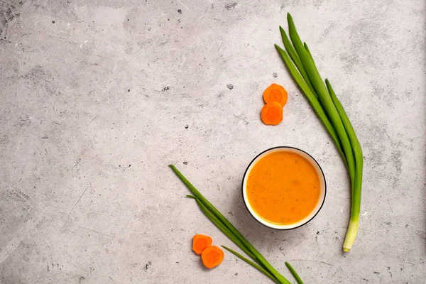 Vejetaryen havuç çorbası, gri beton arka plan, üst manzara.