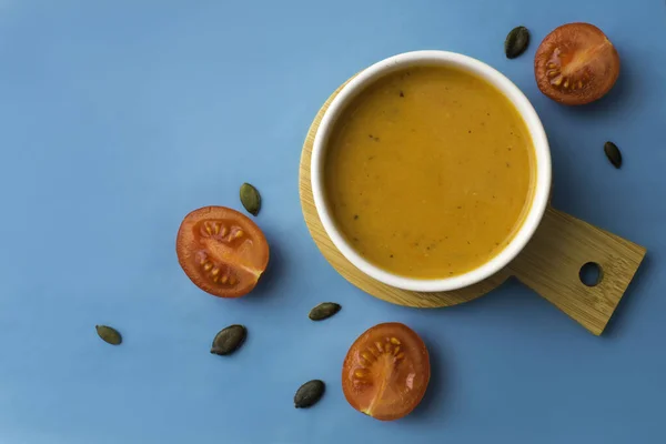 Vejetaryen balkabağı kremalı çorba, mavi arka planda atıştırmalık, üst manzara.