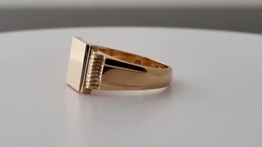 Sarı altın mühür yüzük beyaz masa arkasında dönüyor. 3D canlandırma canlandırması. Mücevher ve süsler için reklam kavramı.