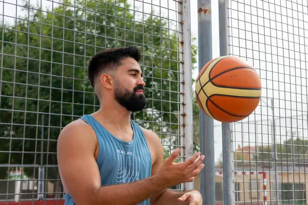 Şehir basketbol sahasında basketbol oynayan mavi tişörtlü bir çocuk.