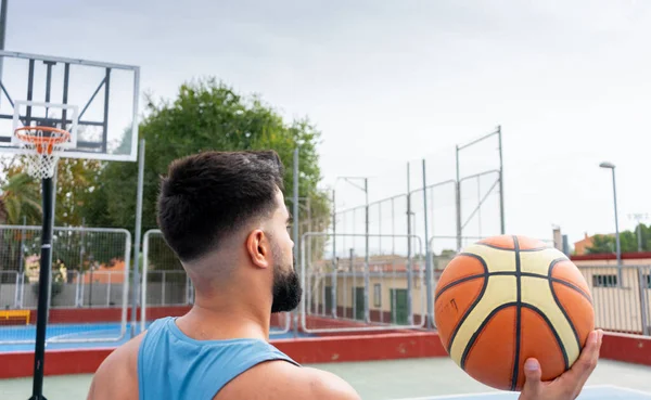 Şehir basketbol sahasında basketbol oynayan mavi tişörtlü bir çocuk.