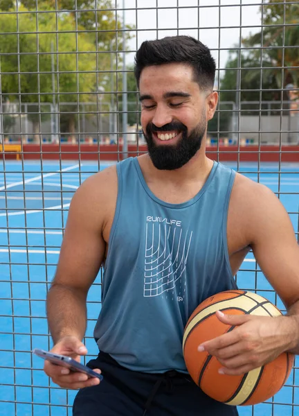 Genç çocuk basketbol oynadıktan sonra cep telefonunu kullanıyor.