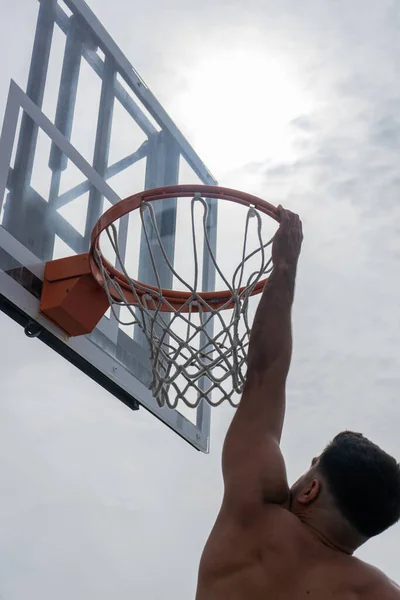 Şehir basketbol sahasında basketbol oynayan mavi tişörtlü bir çocuk.