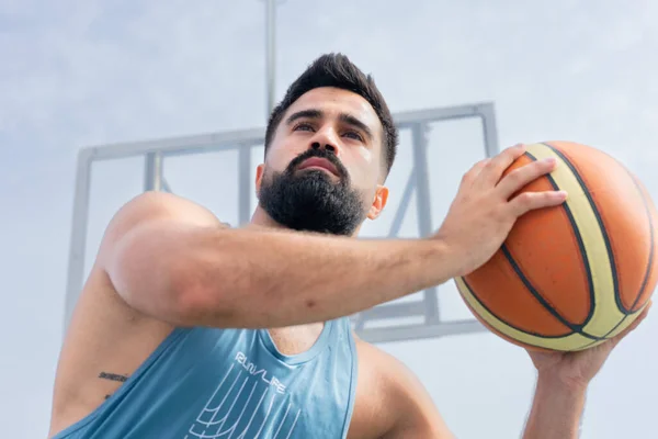 Şehir basketbol sahasında basketbol oynayan mavi tişörtlü bir çocuk.