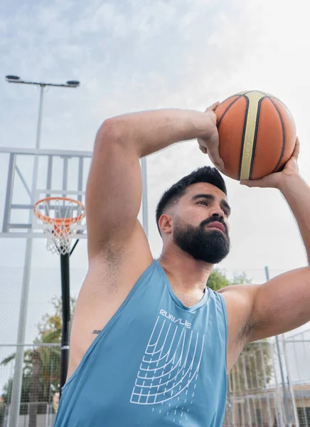 Şehir basketbol sahasında basketbol oynayan mavi tişörtlü bir çocuk.