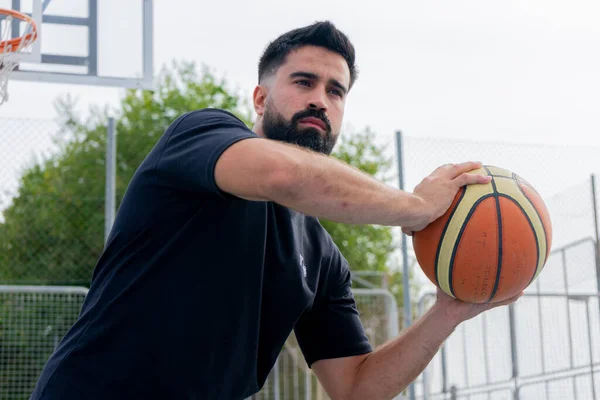 Şehir basketbol sahasında basketbol oynayan mavi tişörtlü bir çocuk.