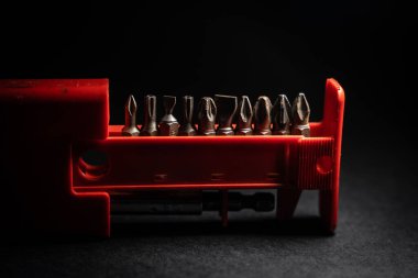 Cıvata, vida, fındık, çamaşır makineleri, mekanik kısım, matkap ucu, kırmızı paket, mavi ışık arka plan. Siyah arka plan. Hassas iş. Marangoz olarak çalış. Doğrama ve inşaat işleri.