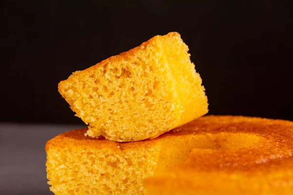 A piece of homemade round Corn Cake, a vegan and healthy delicious cake (Bolo de Fuba), Close Up View, Black Background