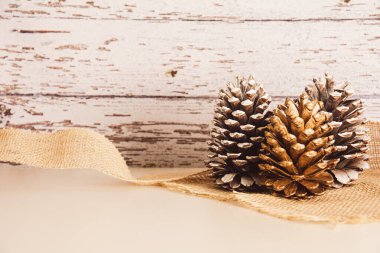 Noel ve Yeni Yıl dekorasyonu, çam kozalakları, altın yay ve ahşap arka plan, kopyalama alanı