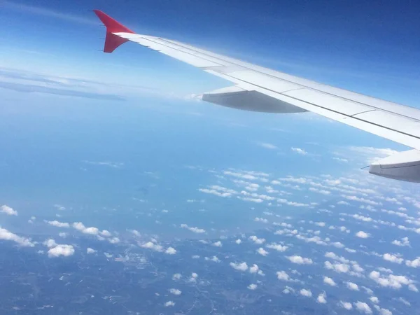 view of the sky above the plane photographed from the window showing the wings of the plane