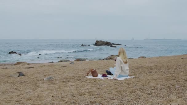 Nő ül a strandon — Stock videók
