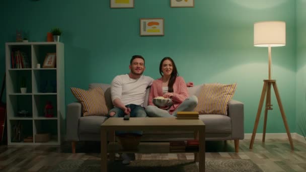 若い幸せなカップルがテレビを見ている — ストック動画