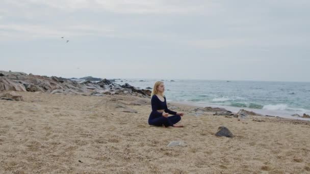 Młoda kobieta medytuje na plaży — Wideo stockowe