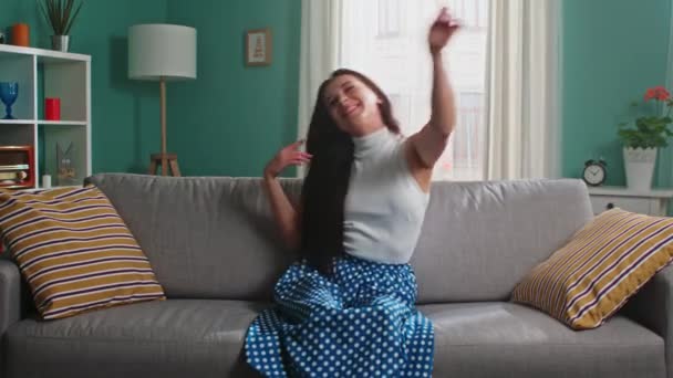 Unga kvinna sitter på soffan och har kul — Stockvideo