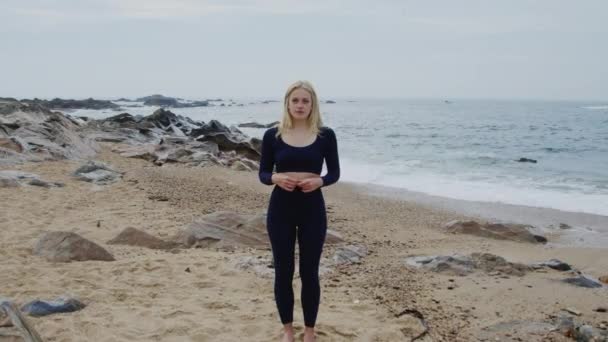 Retrato de la mujer en forma de traje deportivo de pie en la playa — Vídeos de Stock