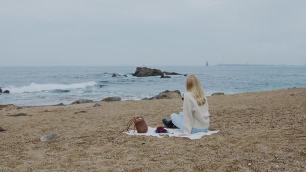 Egy fiatal nő lazít a parton. — Stock videók