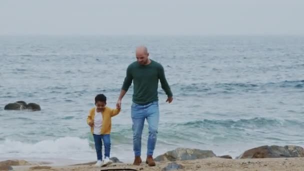 Pai está andando com o pequeno filho na praia do oceano — Vídeo de Stock
