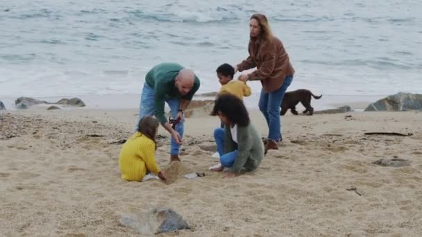 Pais e filhos constroem castelo de areia na praia — Vídeo de Stock