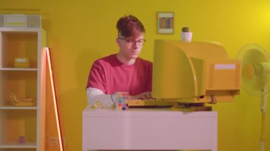 Genç adam bilişim uzmanı Sarı Retro PC 'de çalışıyor.