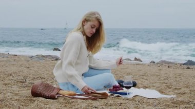 Kadın plajda kitap okuyor.