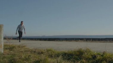 Genç adam dışarıda takla atıyor.