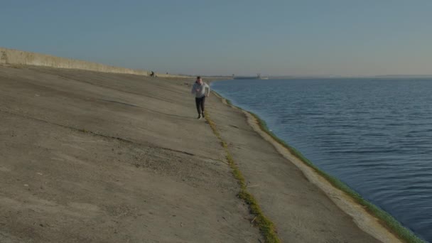 Delgado hombre está corriendo cerca de lago — Vídeo de stock