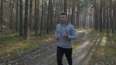Güçlü beyaz adam ormanda koşuyor.