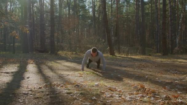 Молодой человек делает отжимания в лесу — стоковое видео
