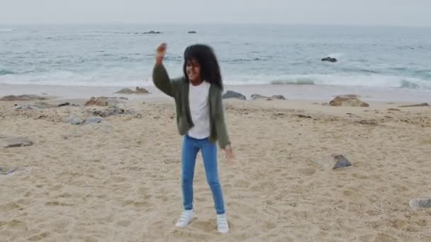Маленькая смешная девочка танцует на пляже — стоковое видео