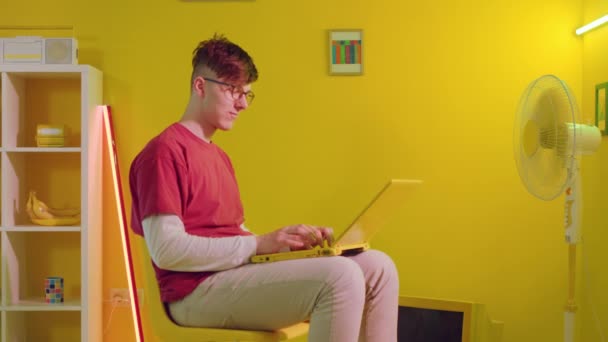 Hombre con gafas está escribiendo en el ordenador portátil amarillo — Vídeos de Stock