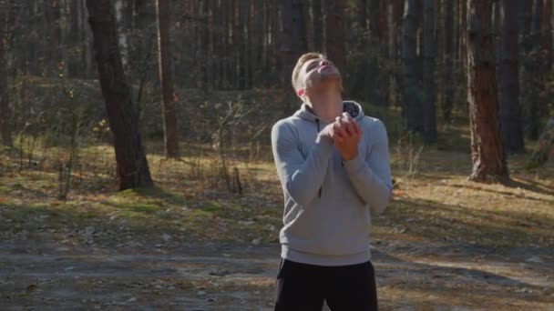 Hombre joven se calienta en el bosque — Vídeo de stock
