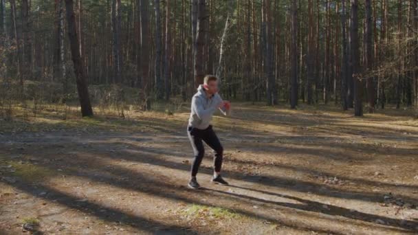 Молодой человек тренируется в лесу — стоковое видео