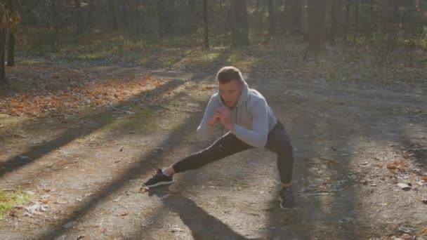 Homem está esticando as pernas antes do treino — Vídeo de Stock
