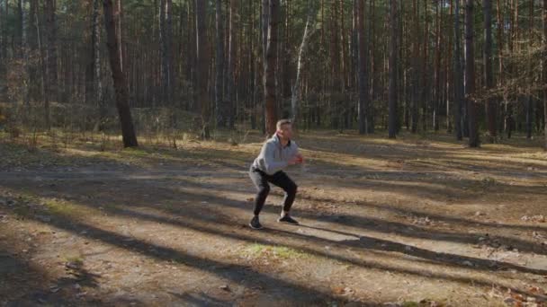 Молодий людина є squatting в ліс — стокове відео