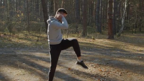 Un tânăr se încălzește în pădure înainte de antrenamentul de dimineață — Videoclip de stoc