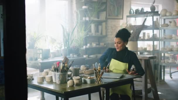 女性は陶器スタジオでラップトップを使用しています — ストック動画