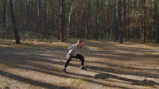 Αθλητής θερμαίνεται στο δάσος πριν από το πρωινό τρέξιμο — Αρχείο Βίντεο