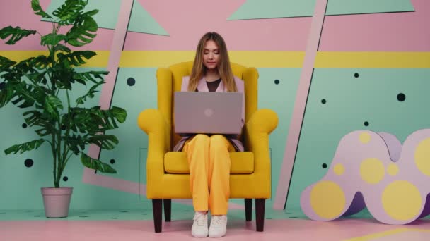 Γυναίκα σε κίτρινο πολυθρόνα χρησιμοποιεί Laptop — Αρχείο Βίντεο